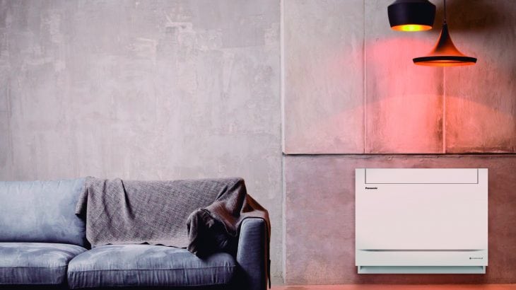 gulvmodell varmepumpe i hvitt ved siden av grå sofa. moderne vegger og sorte lamper som henger over varmepumpen